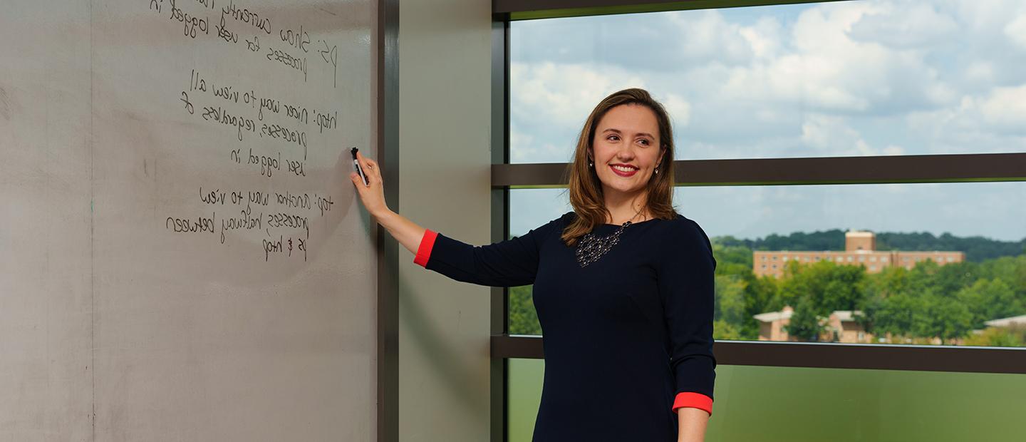 A woman writing on a white board in a classroom